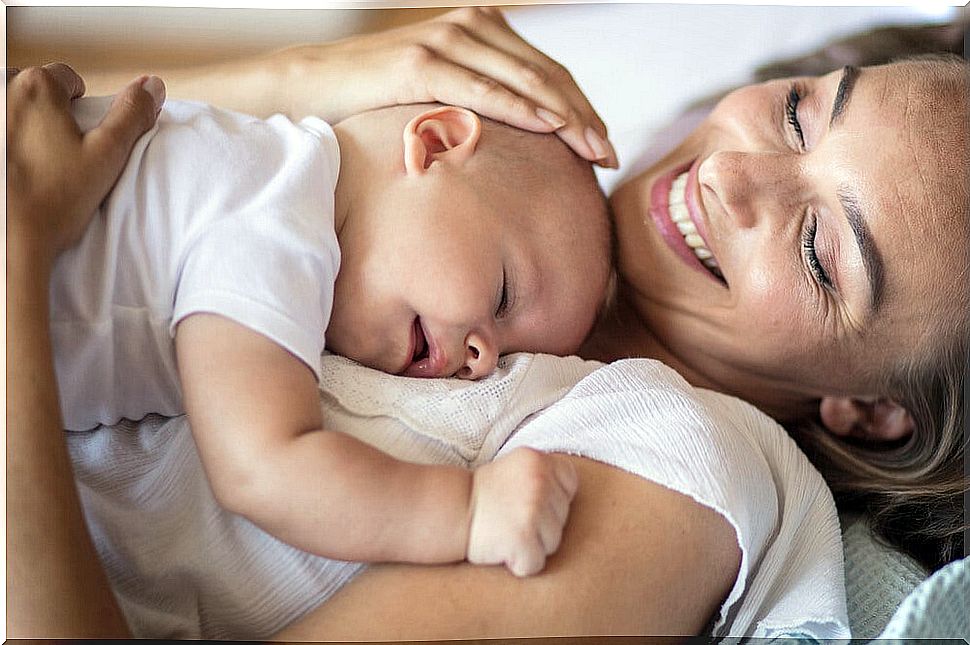 Mother hugging her baby and smiling with happiness.