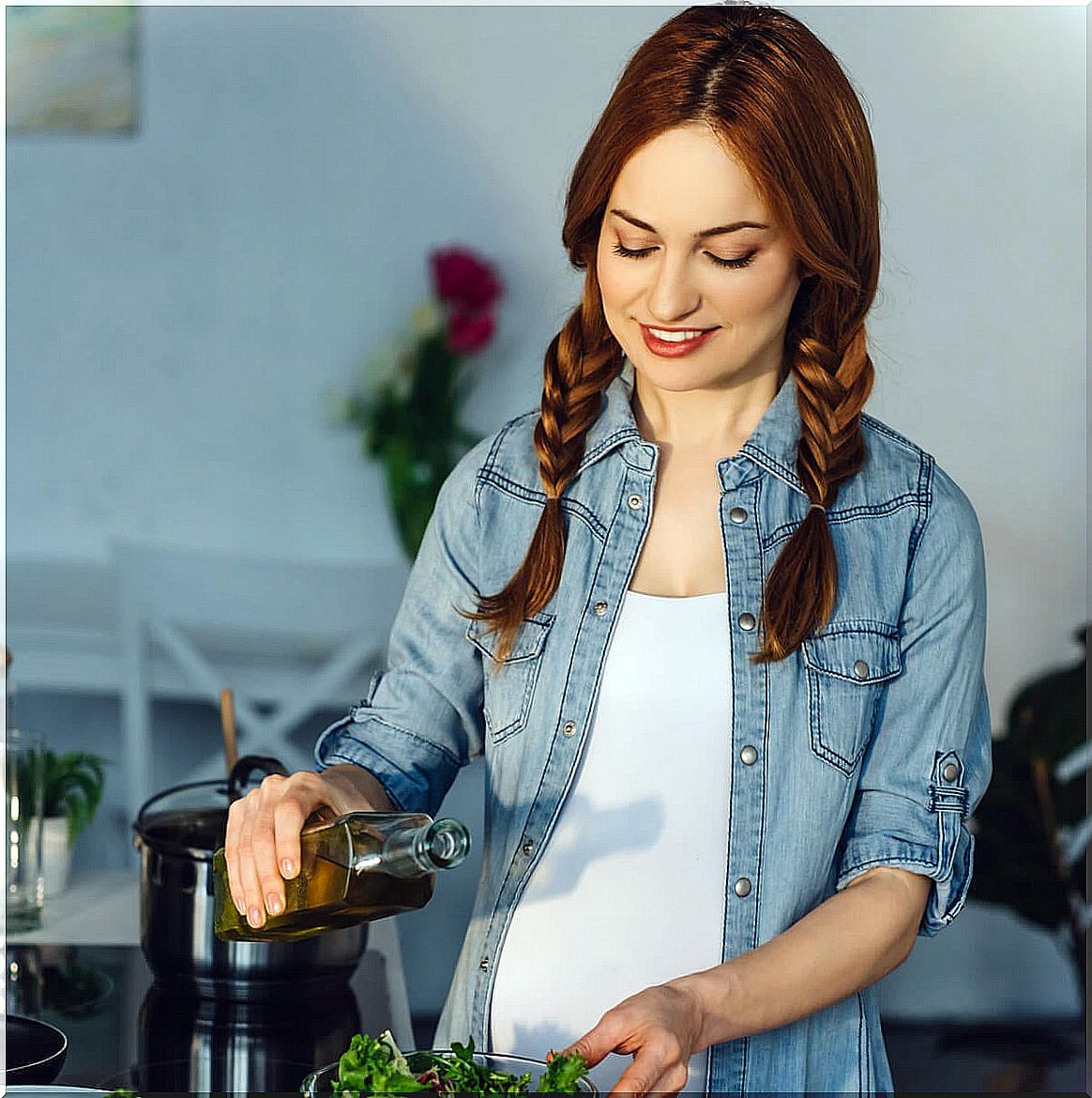 Pregnant woman pouring olive oil into her salad.