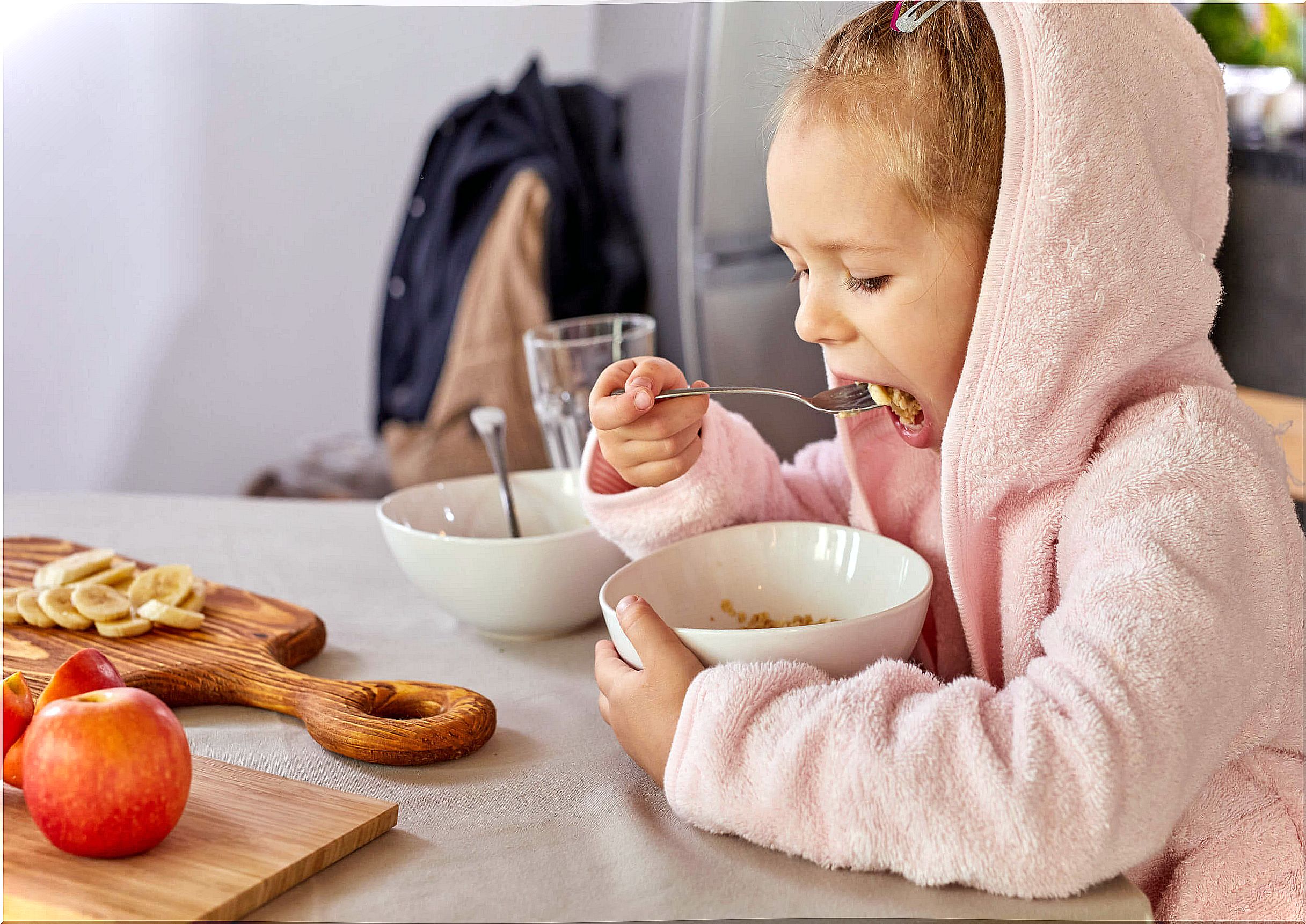 Little girl eating oatmeal and fruit for snack.