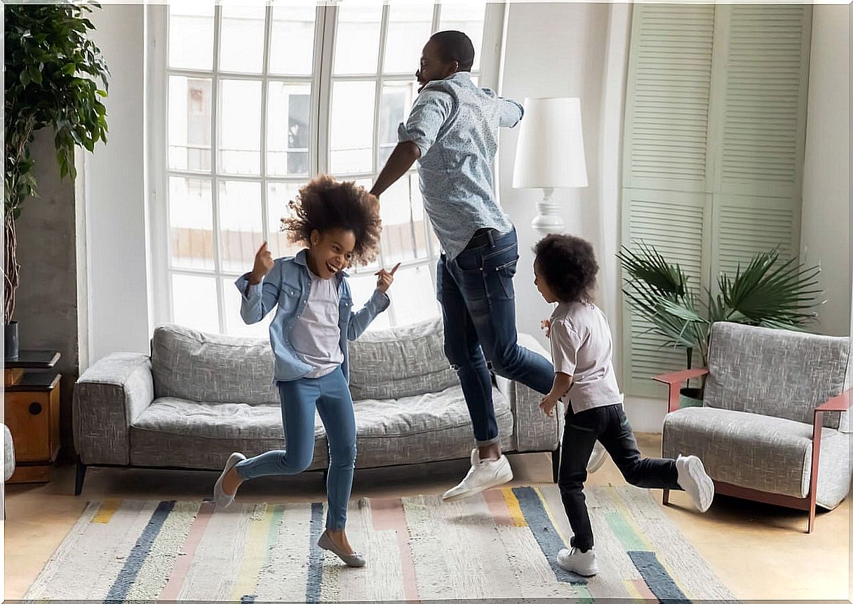 Father dancing with his children in the living room at home.