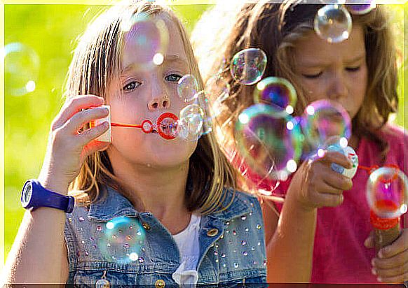 girls blowing soap bubbles in summer