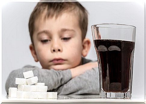 Boy looking at the sugar cubes next to his glass of soda with synthetic sweeteners.