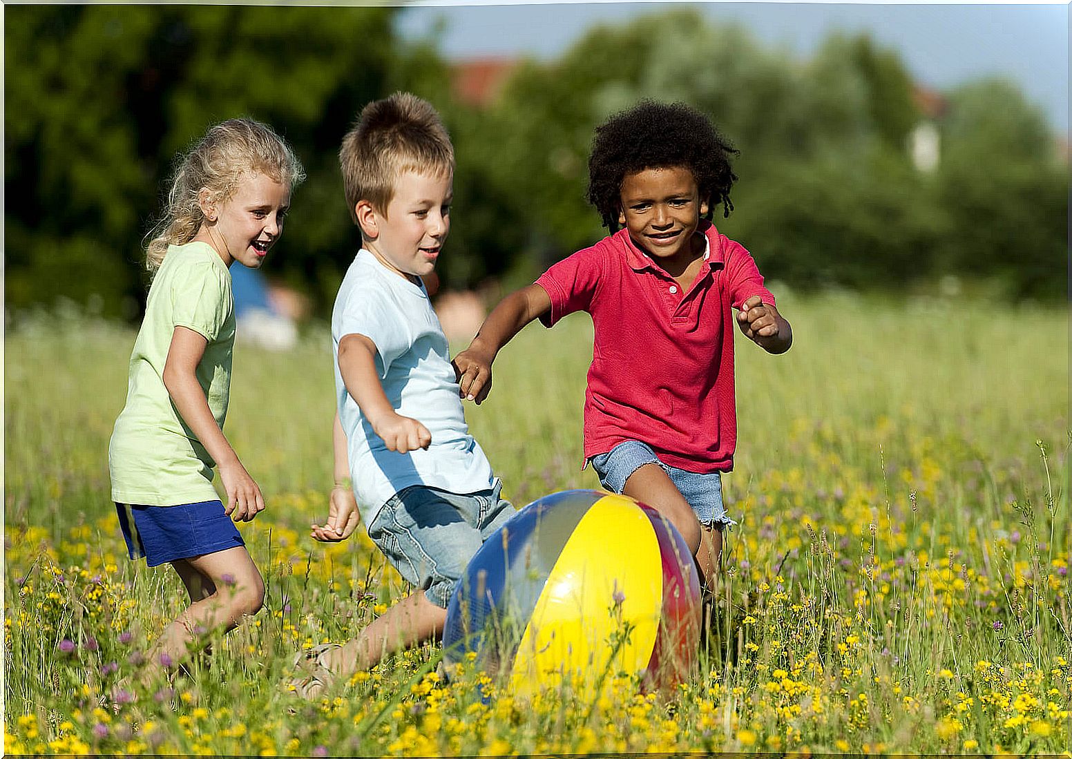 Children playing with the ball outdoors in summer.