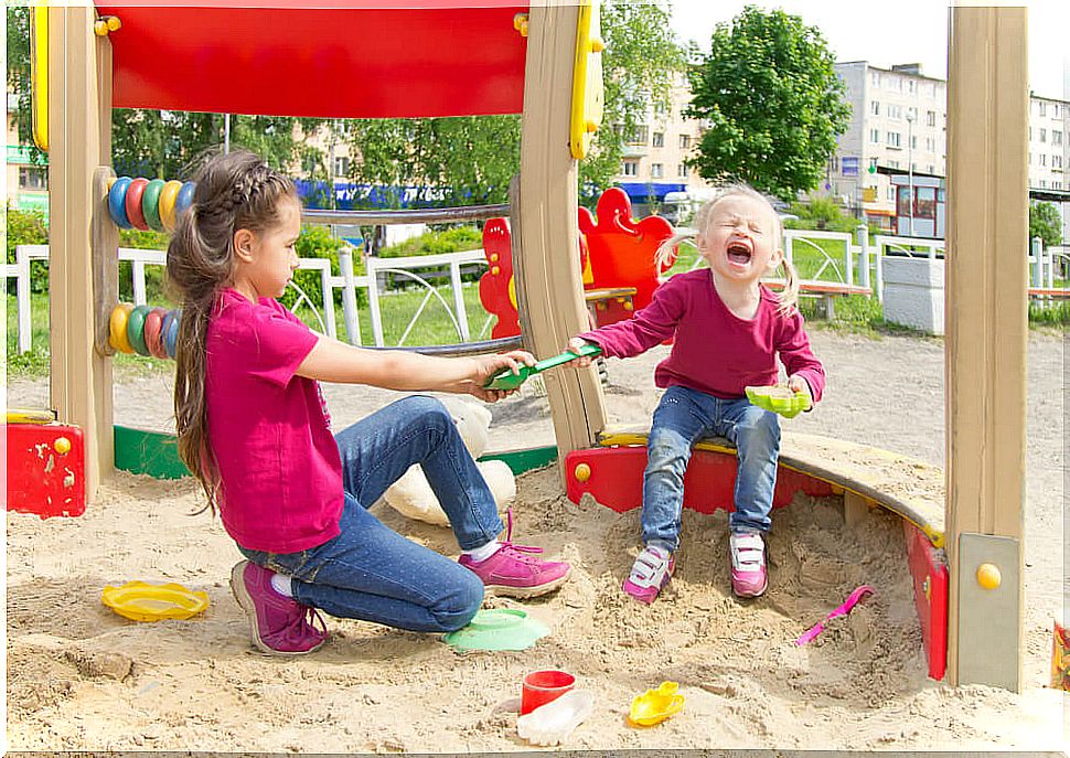 Girls fighting for a shovel in the park without resolving their conflicts.