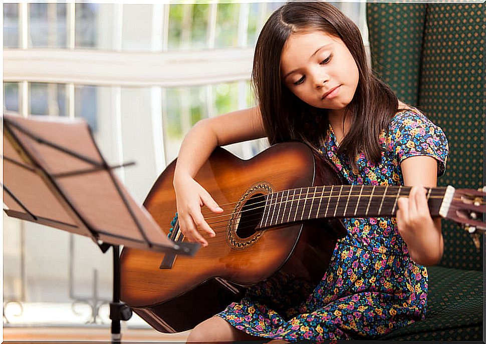 Girl learning to play the guitar in one of the extracurricular activities she attends.