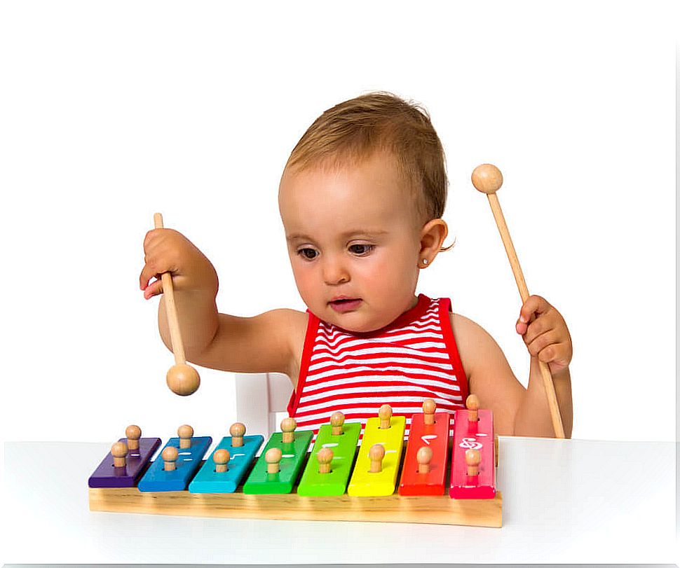 Little girl playing the xylophone because music is beneficial for children's cognitive development.