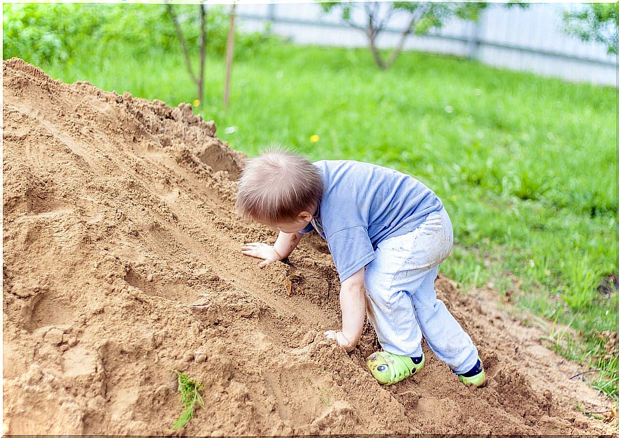 Child climbing a mound of earth to learn to take risks.