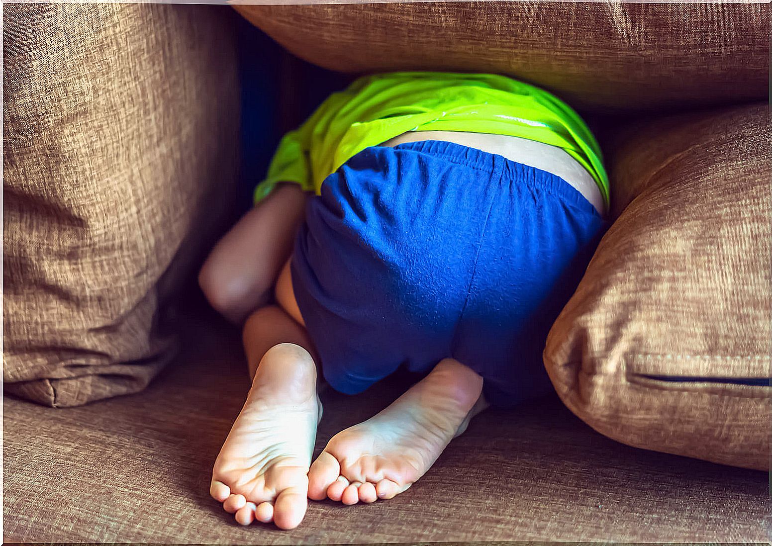 Introverted boy hiding on the couch.