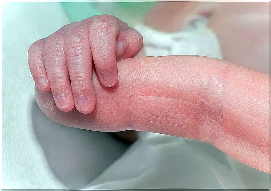 Newborn baby grabbing his mother's finger.