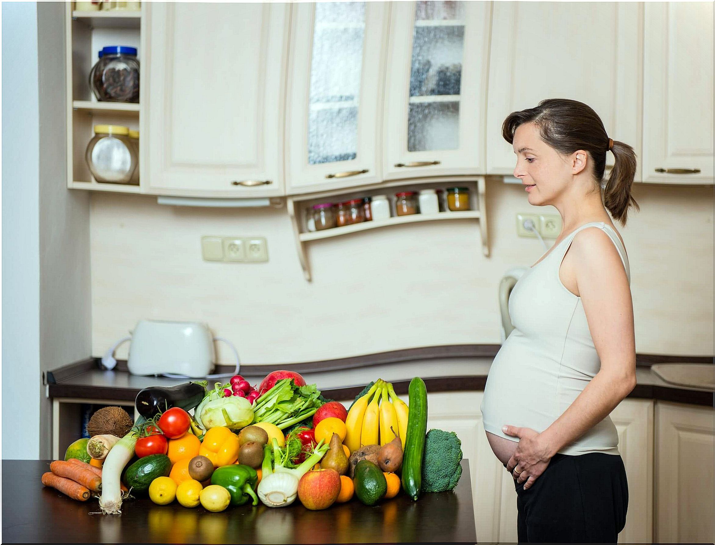 Pregnant woman after making a healthy shopping with green leafy vegetables.