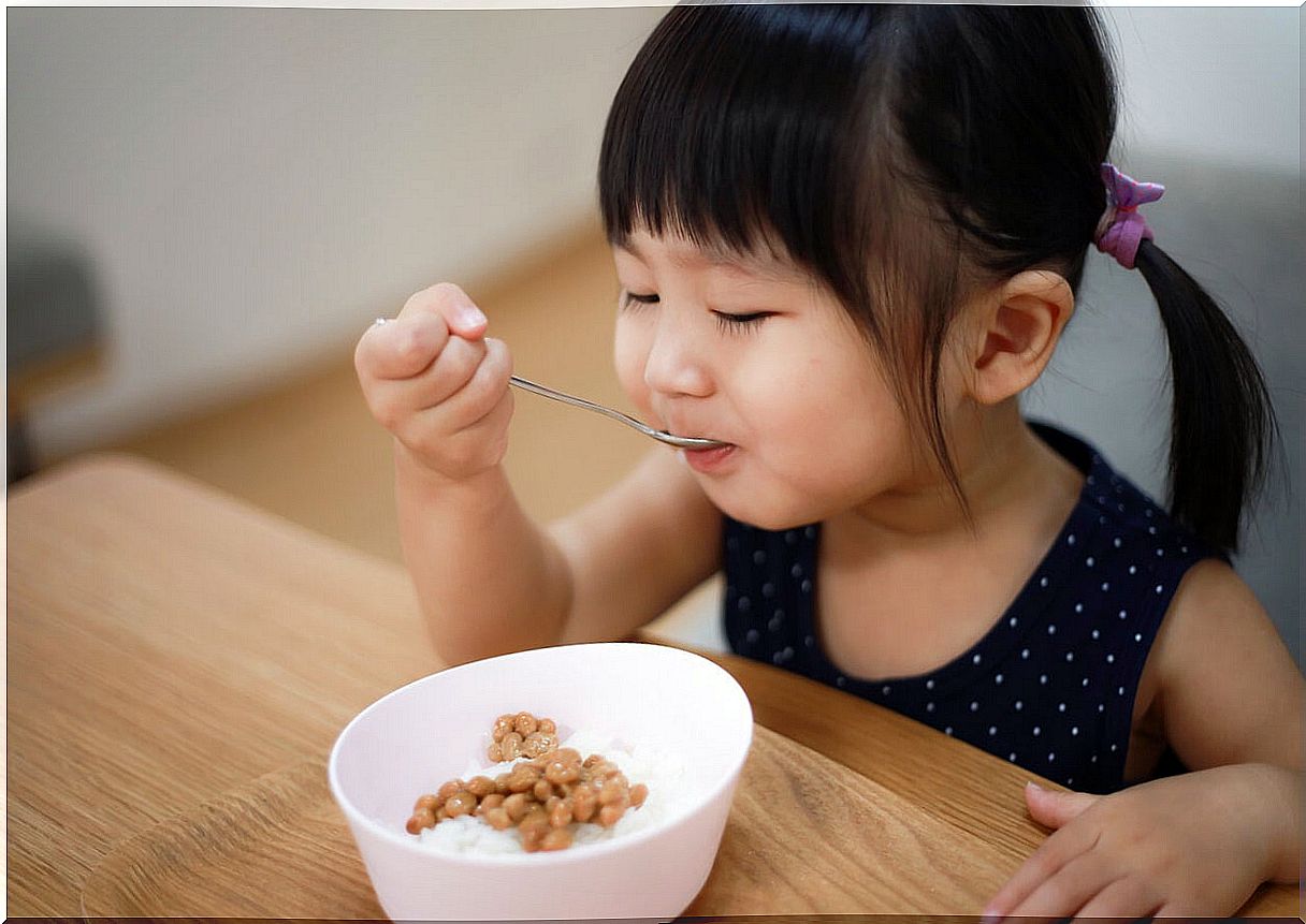 Little girl eating rice and legumes.